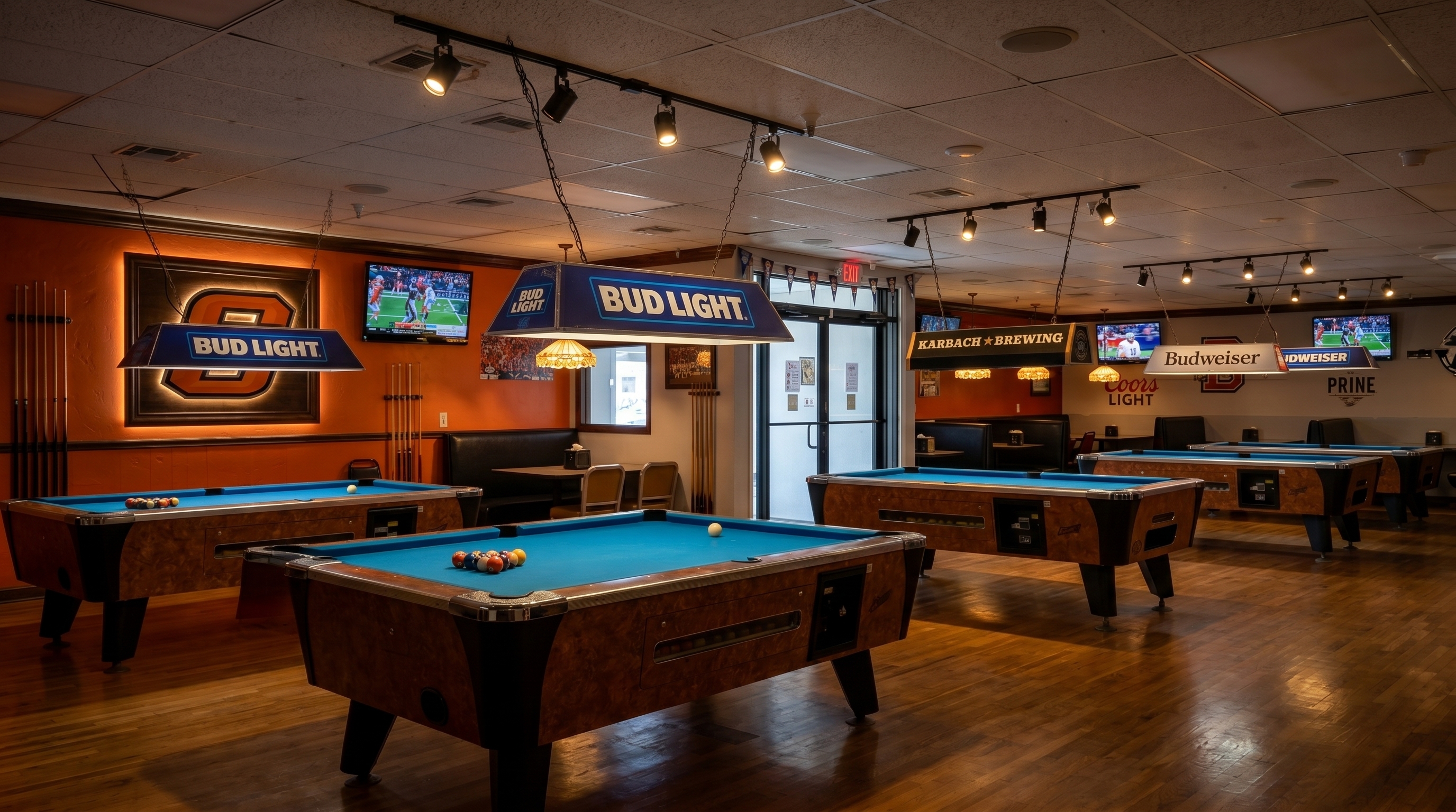 Pool tables under bar lamps with big-screen TVs in the Red Apple sports bar