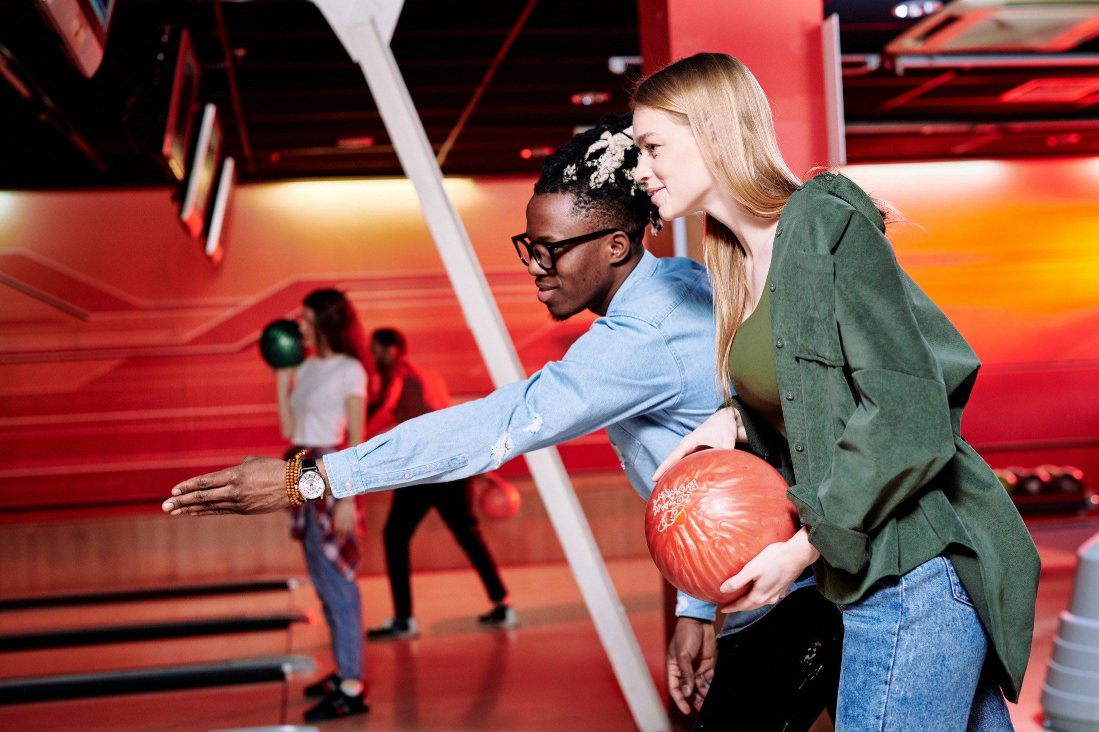 A bowler guiding a teammate's aim down the lane on league night